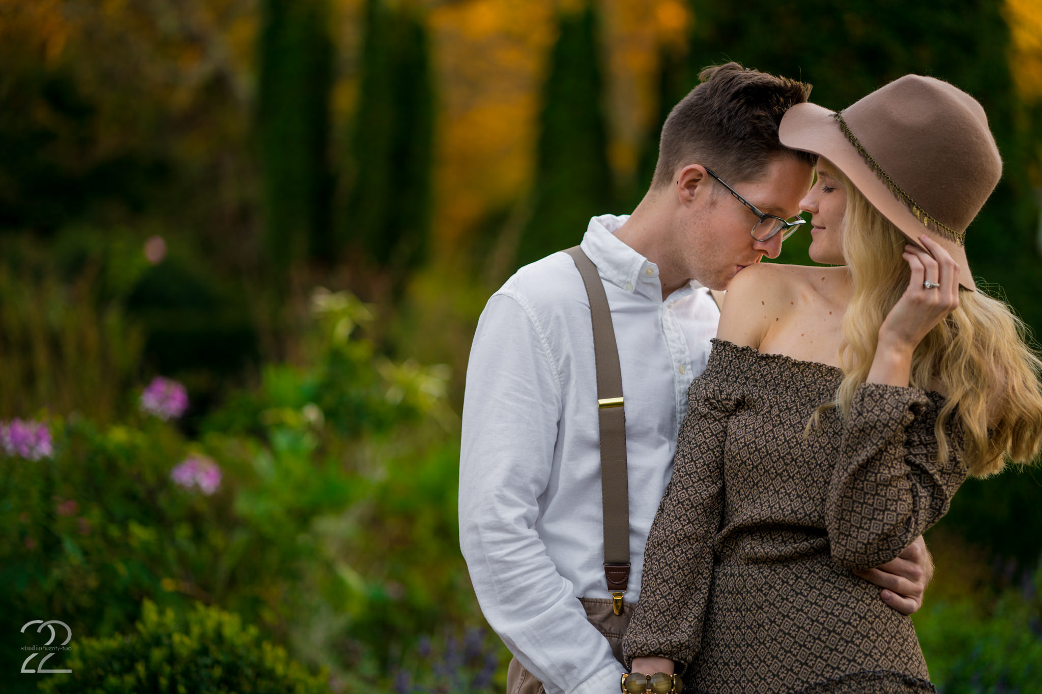 Man kisses woman's shoulder as he hugs her in a garden at Wegerzyn Garden Metropark by Dayton Wedding Photographer Studio 22 Photography